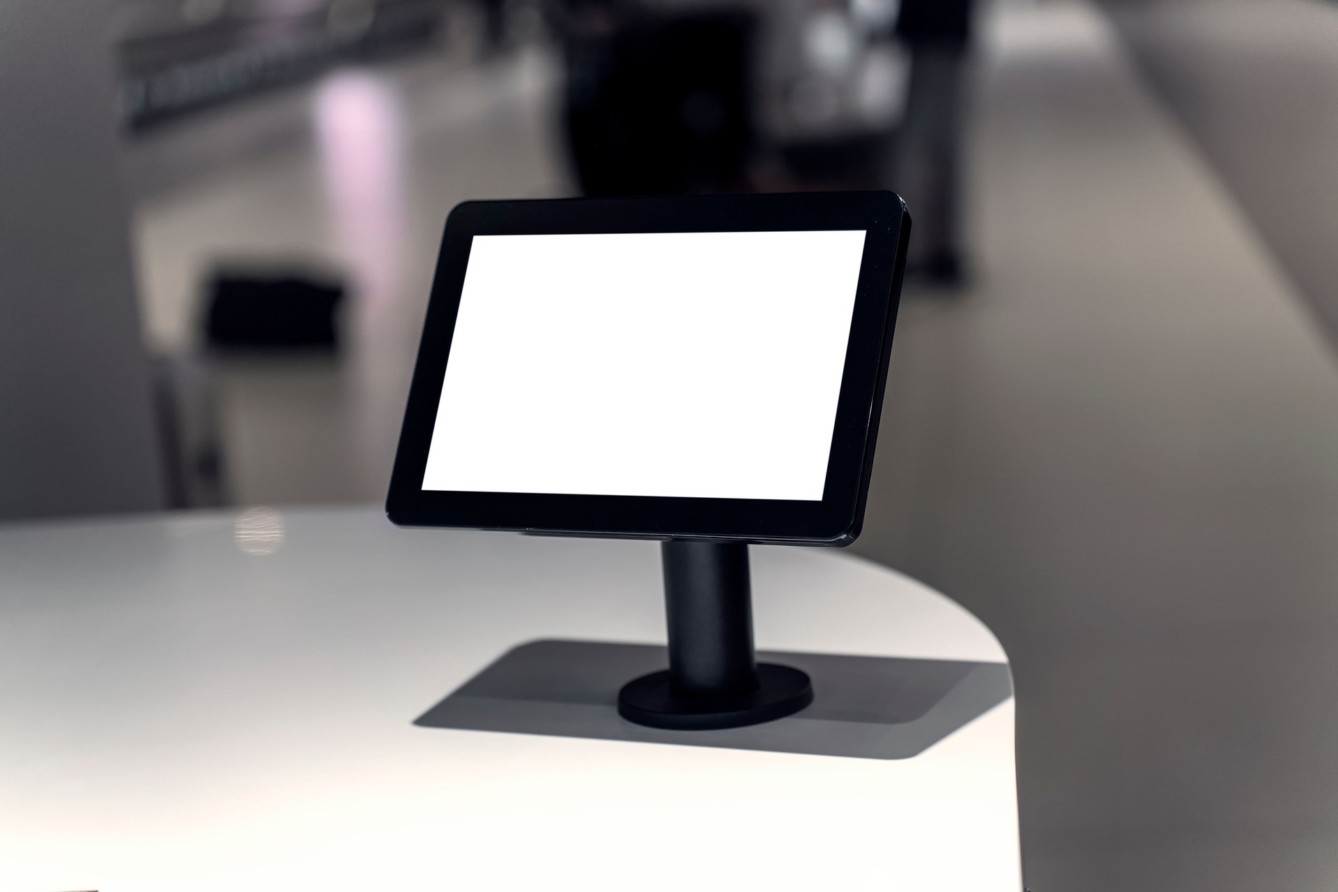 Empty tablet screen mounted on stand in modern indoor setting, ideal for digital signage or interactive display. Ready for mockup or promotional content in retail or business environment