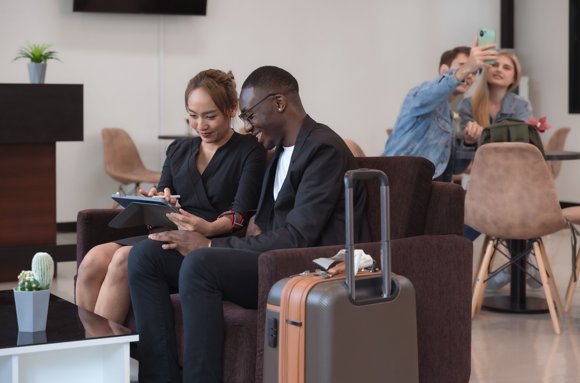 Business man and woman using digital tablet while waiting in airport lounge for travelling on business trip