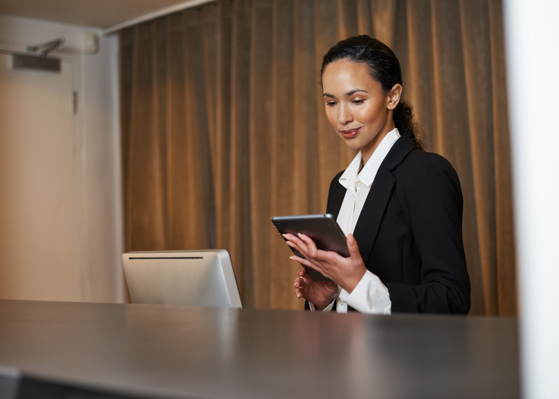 Professional Receptionist Using Digital Tablet at Front Desk Checking in Hotel Client